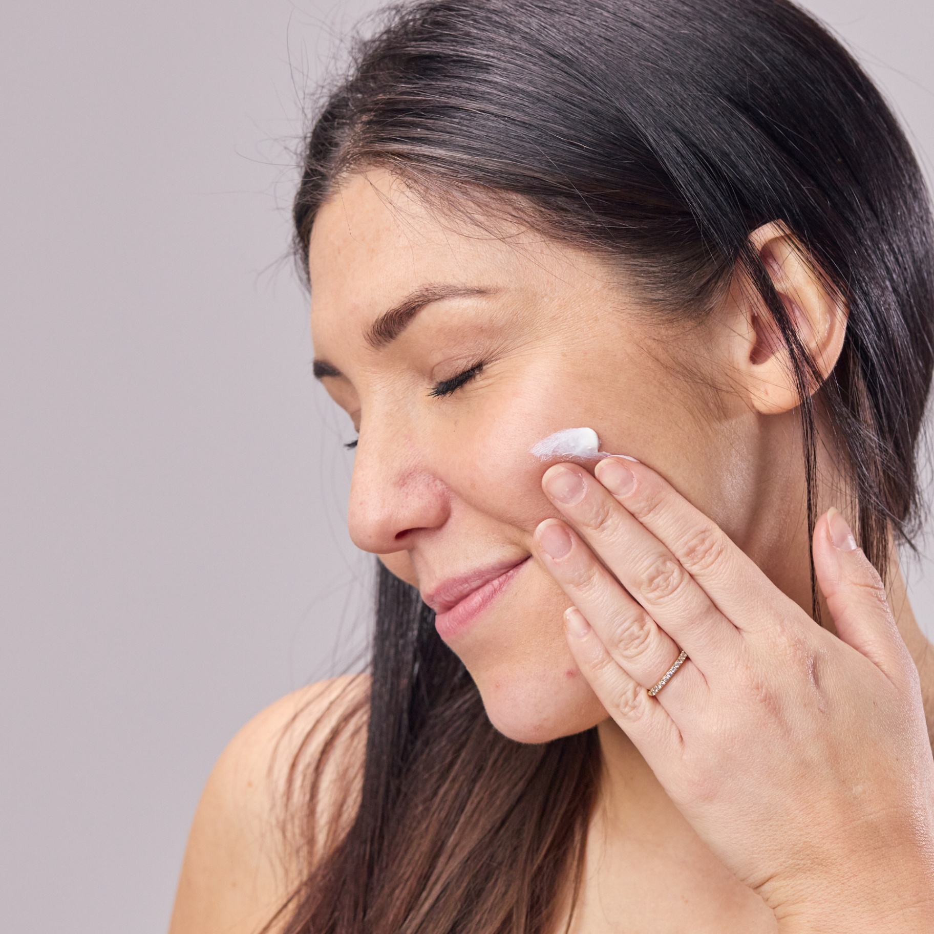 Woman applying cream to her cheek